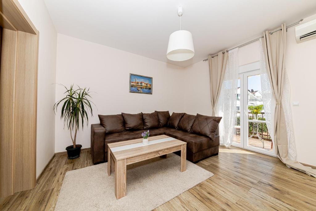 ein Wohnzimmer mit einem braunen Sofa und einem Tisch in der Unterkunft Apartments Katarina in Ðenovići