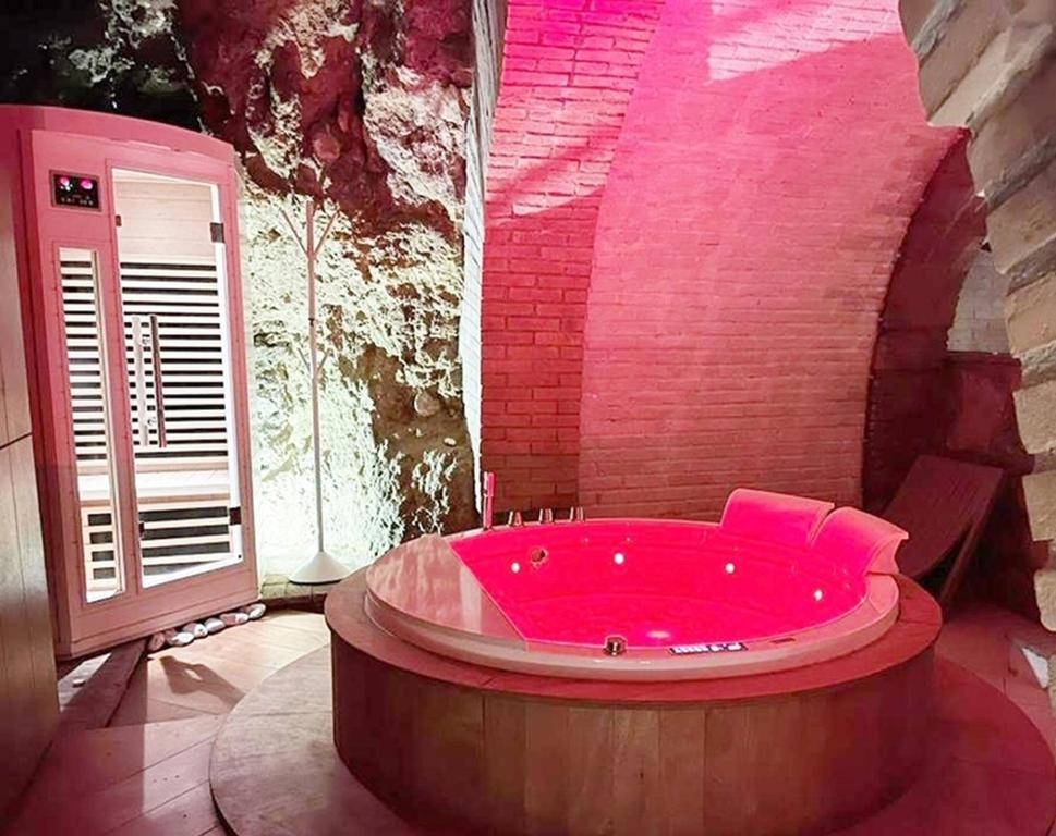 Una gran bañera roja en una habitación con una pared de ladrillo en Suite In Love 21, en Casale Marittimo