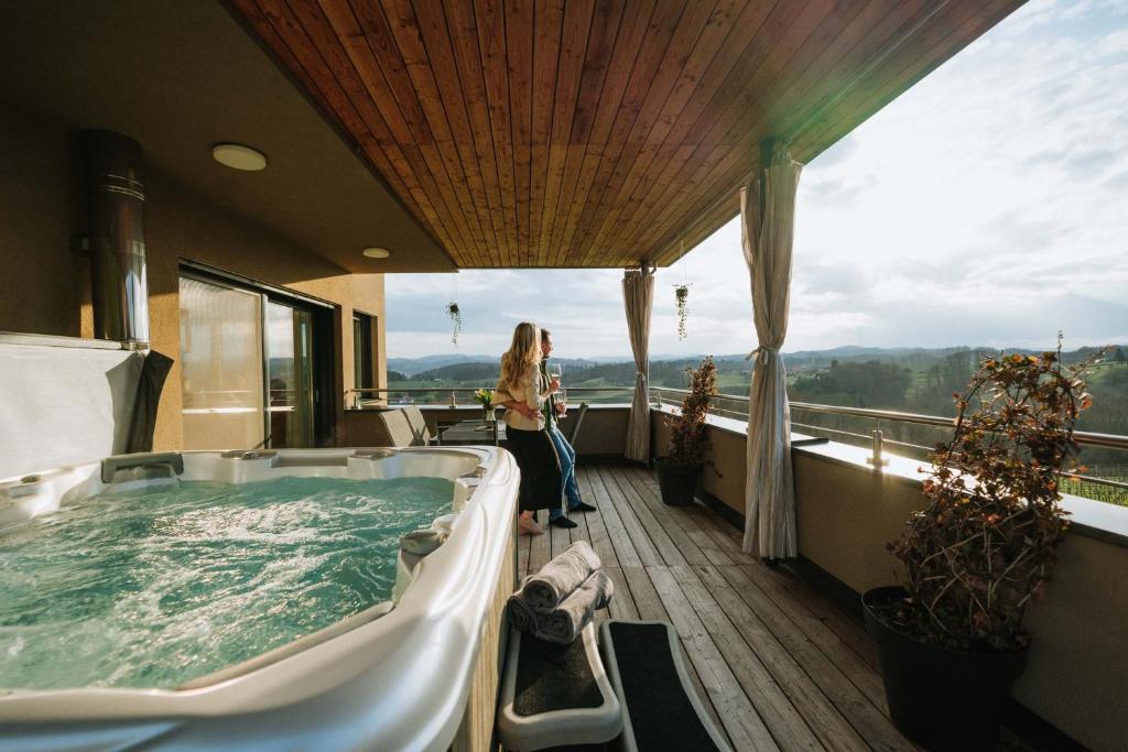 a woman standing in a hot tub on a balcony at Weingut Zweytick Lodge Vinoment in Ehrenhausen