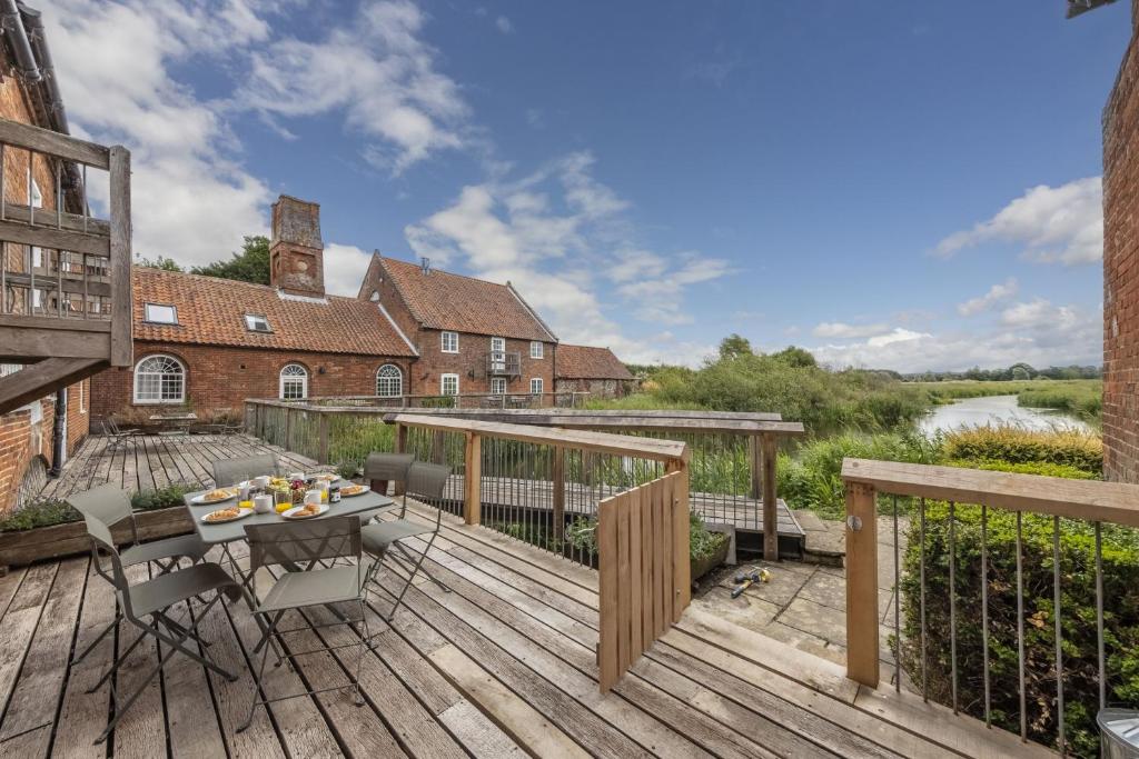 a wooden deck with a table and chairs on it at Water Mill House in Burnham Market