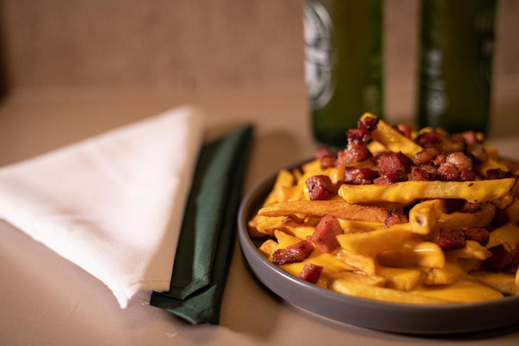 a bowl of food with cheese fries and bacon at Motel Stilo - Adults Only in Contagem