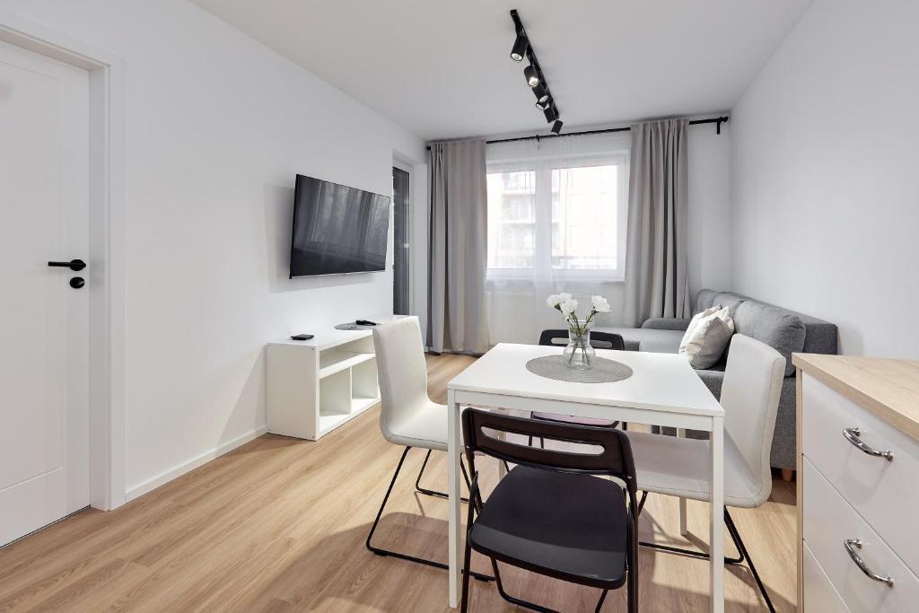 a kitchen and living room with a white table and chairs at Sielawy Modern Apartment by BookingHost in Poznań