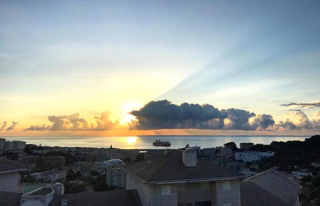 un coucher de soleil sur une ville avec un bateau dans l'eau dans l'établissement Bastia 2p neuf vue mer grande terrasse, à Bastia