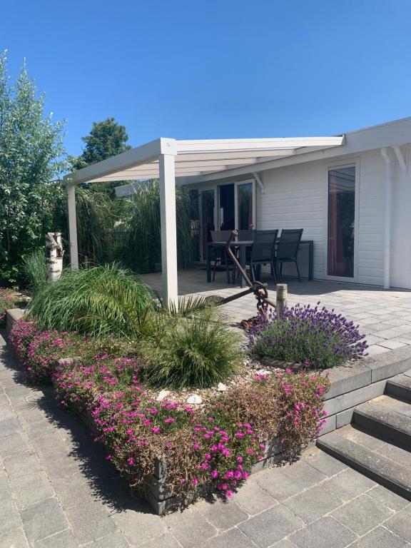 eine Terrasse mit Blumen und Pflanzen vor einem Haus in der Unterkunft Ferienchalet „Sundowner“ in Breskens