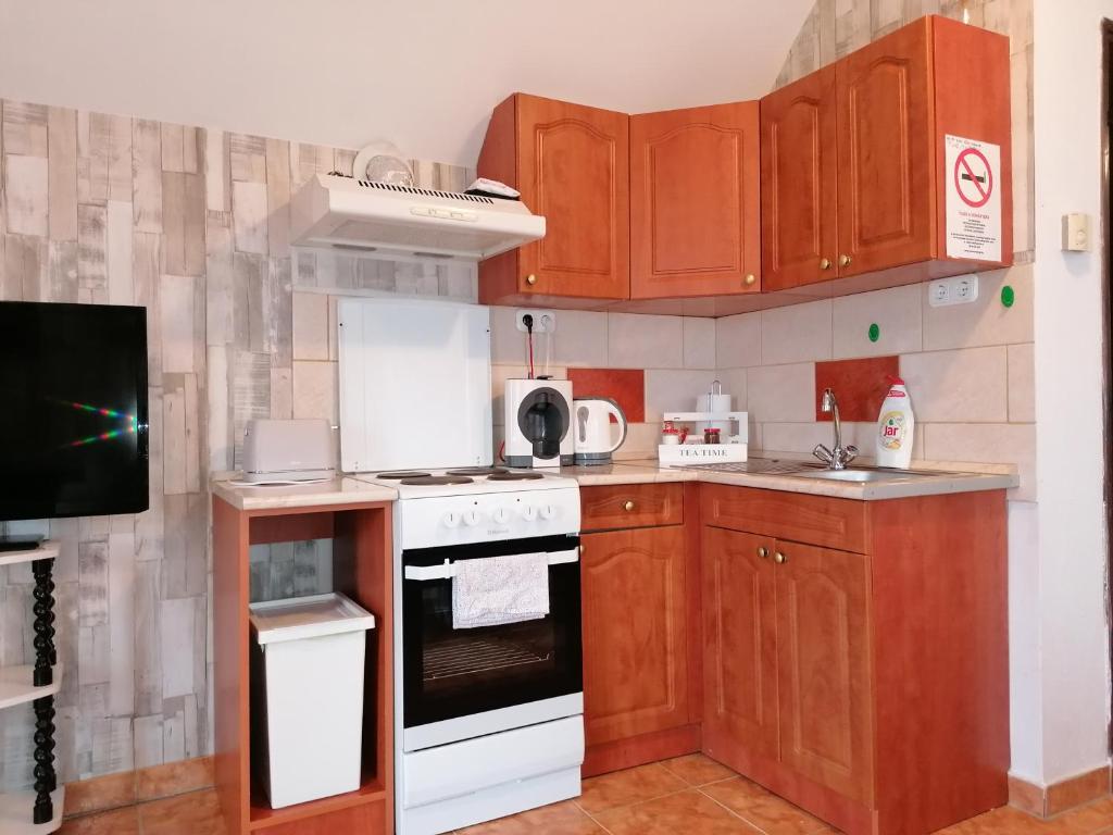 a kitchen with wooden cabinets and a white stove top oven at A nyugalom szigete Tabán Apartman in Dunakeszi