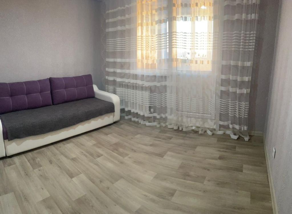 a living room with a couch and a window at Квартира in Pavlodar