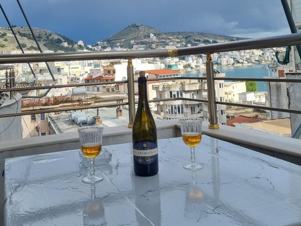 a bottle of wine and two glasses on a table at Lea Apartament in Sarandë