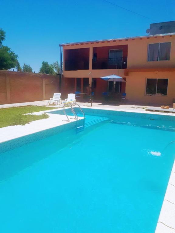 a swimming pool with two chairs and a building at Departamentos San Benito in Malargüe