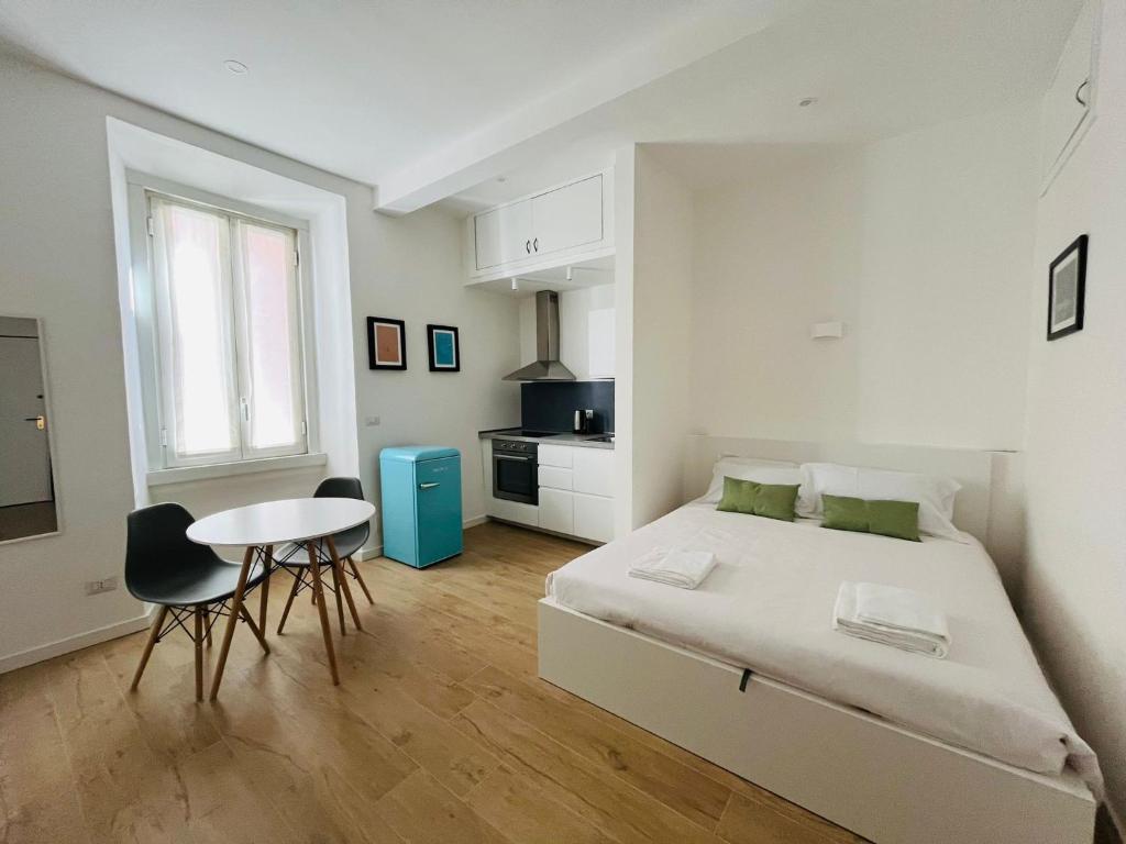 a white bedroom with a bed and a table at Lomat Apartment in Milan