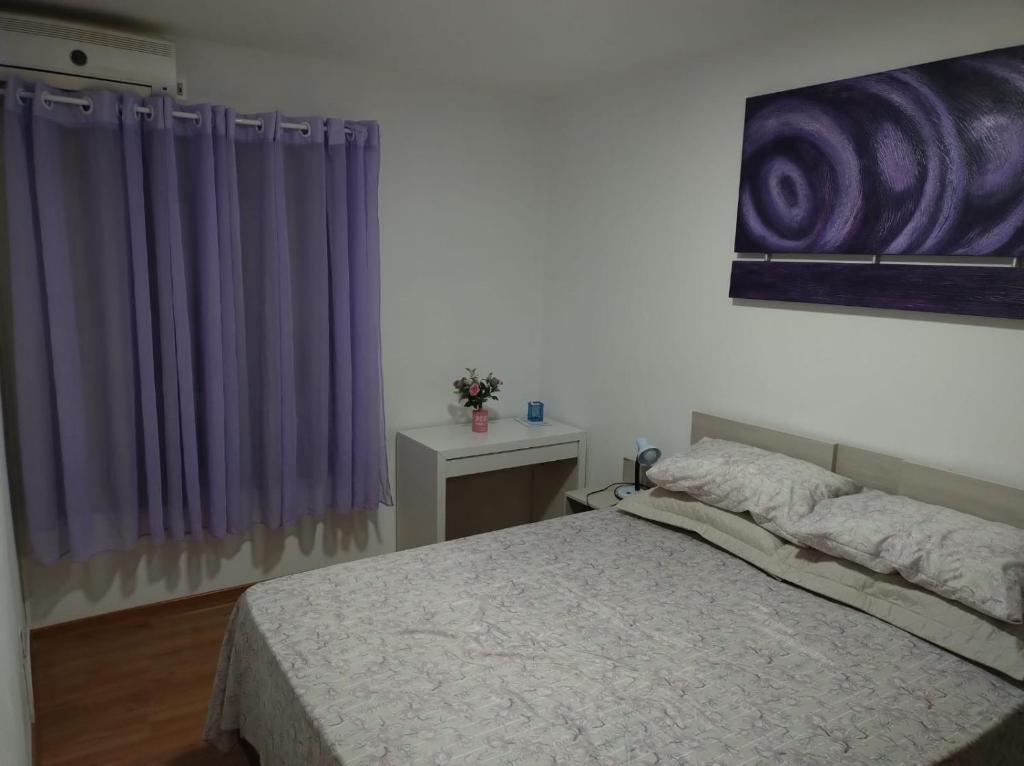 a bedroom with a bed and a purple curtain at Apartamento Cantinho do Aconchego-Nova Petrópolis in Nova Petrópolis