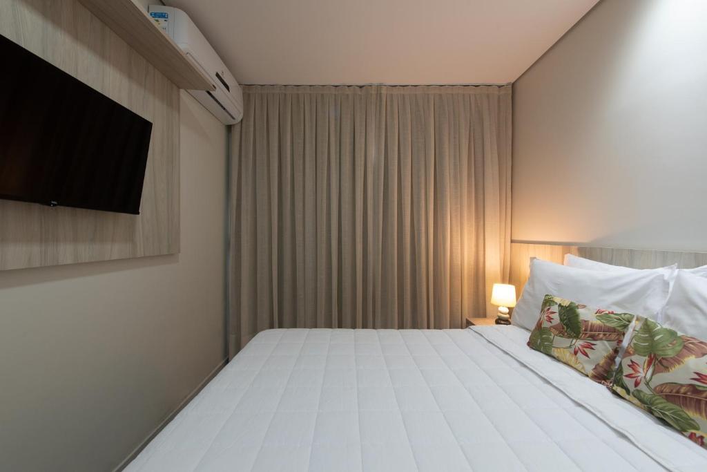 1 dormitorio con 1 cama y TV en la pared en Pousada Tartarugas Marinhas en Fernando de Noronha