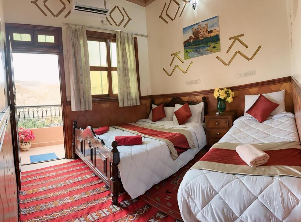 a bedroom with two beds and a balcony at Kasbah La Famille Berbère in Boumalne