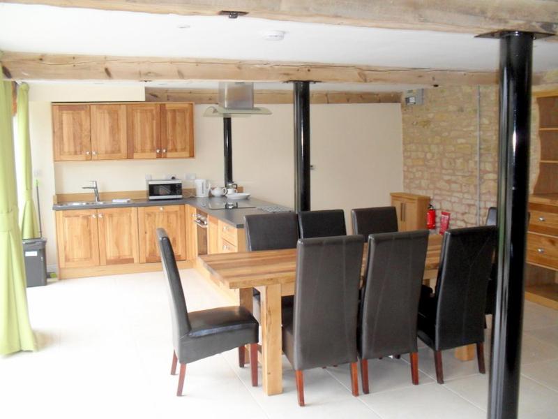 a kitchen with a wooden table and black chairs at Rats Retreat at Tove Valley Cottages in Towcester