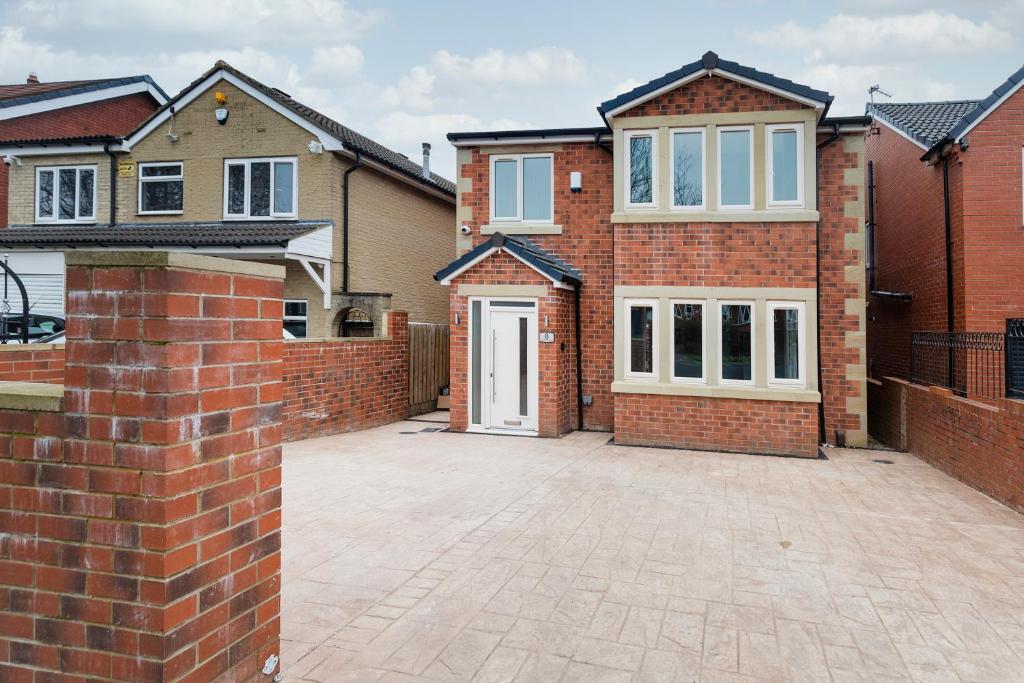 uma casa de tijolos com uma entrada e uma porta branca em Entire 4 bed new build detached house in Yorkshire em Batley Carr