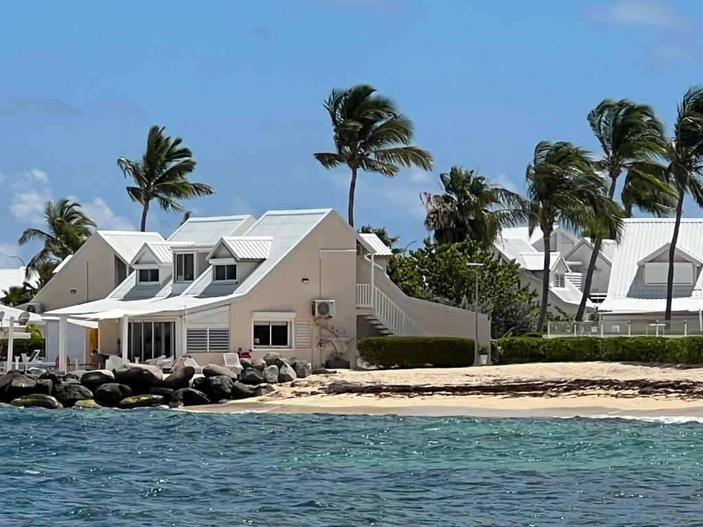 a white house on a beach with palm trees at Sweet Home SXM Baie Nettlé Pieds dans l'eau in Saint Martin