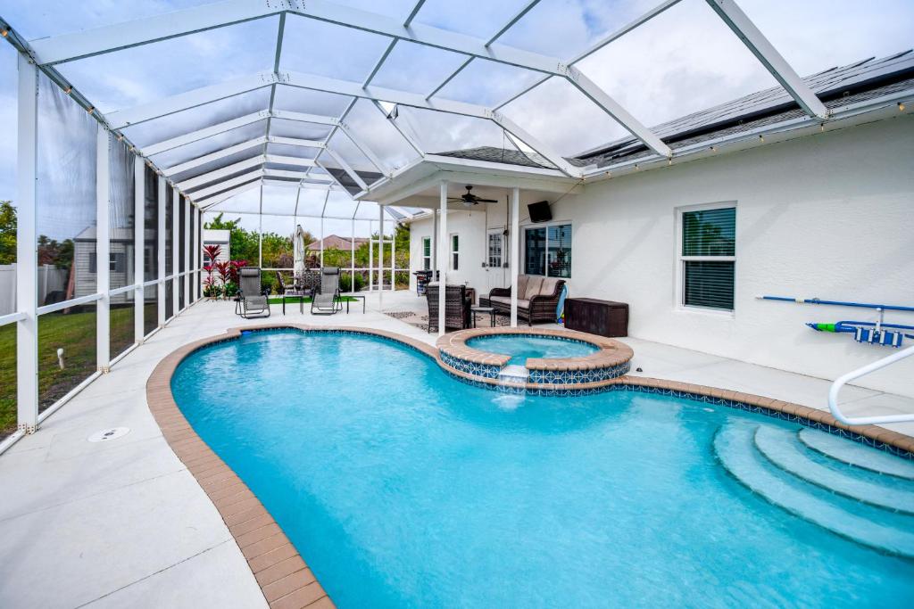 an indoor swimming pool with a glass roof at Lovely Lehigh Acres Home with Lanai, Pool and Spa! in Lehigh Acres