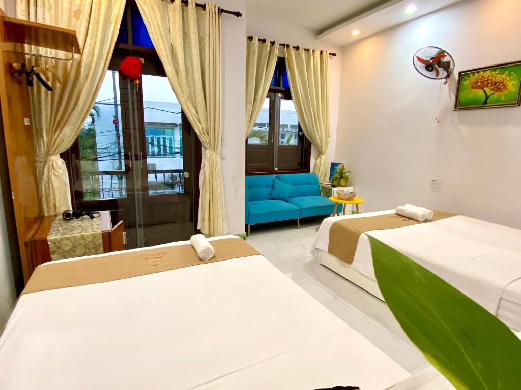 een slaapkamer met 2 bedden en een blauwe bank bij Bui Family Homestay in Hội An