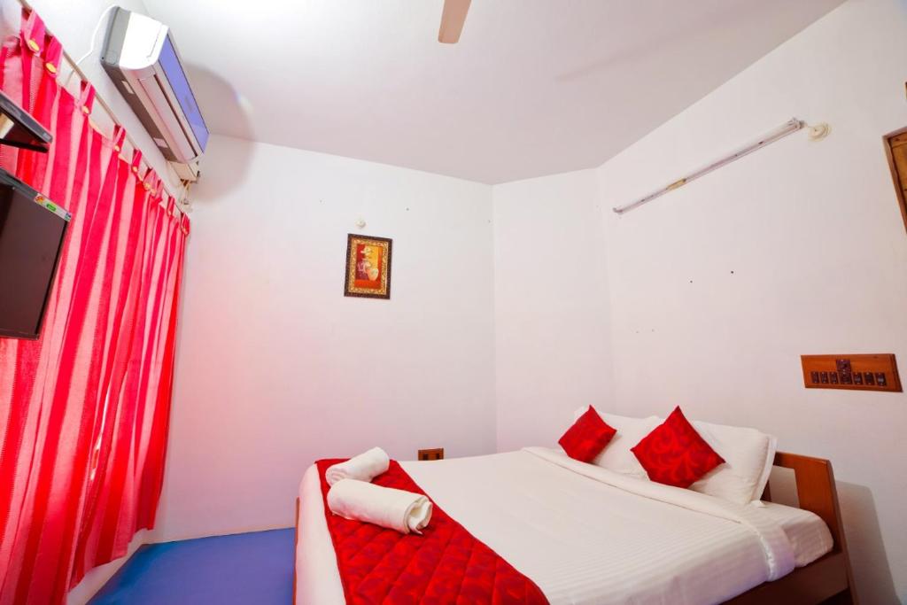 a bedroom with a bed with red curtains at Sai White Villa Pondicherry in Puducherry