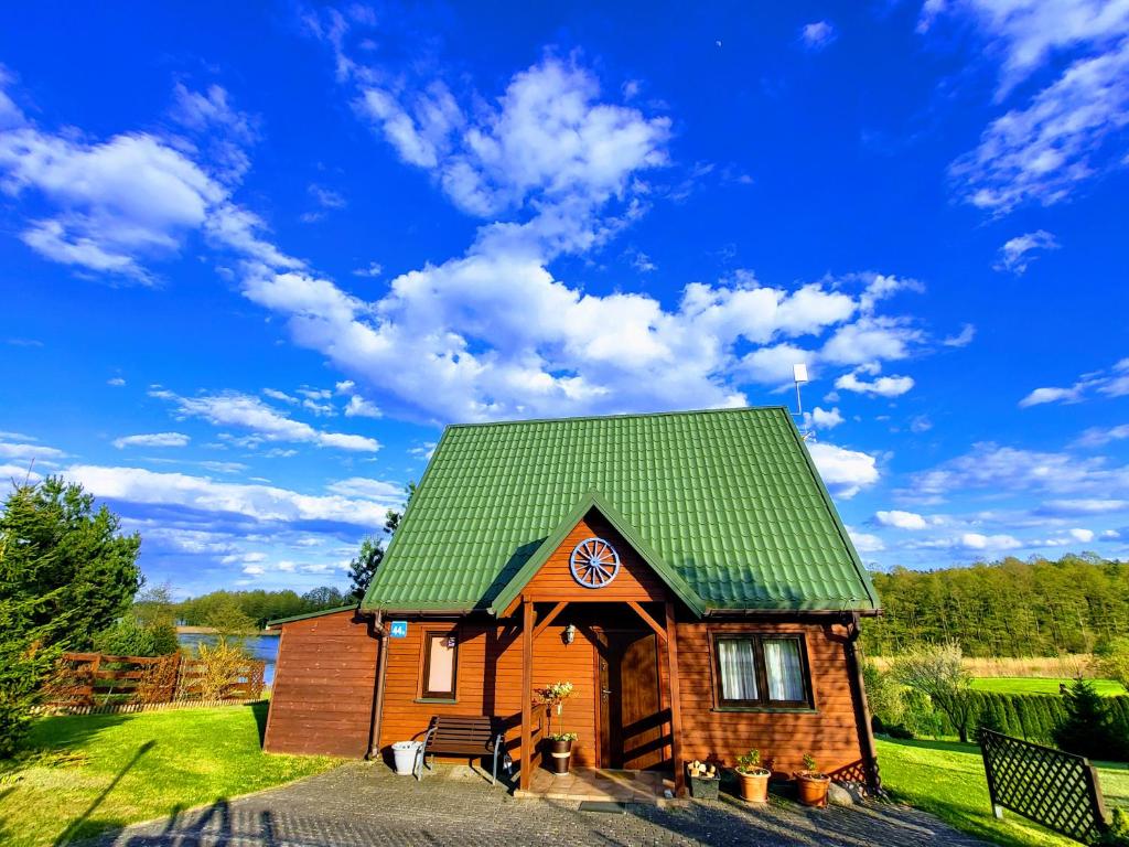 une petite maison en bois avec un toit vert dans l'établissement Dom Niebieski nad jeziorem Orzyskim, à Skomack Wielki