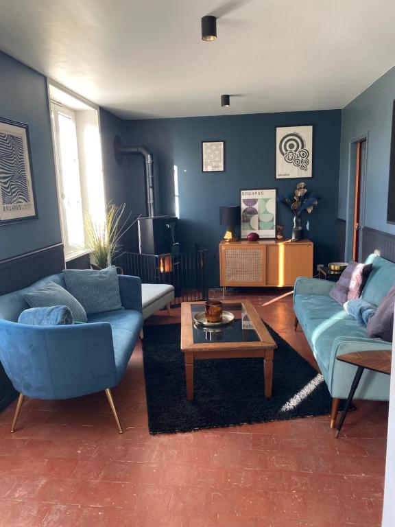 una sala de estar con 2 sofás azules y una mesa. en Maison au cœur d'une ancienne ferme à BAYEUX, en Monceaux-en-Bessin
