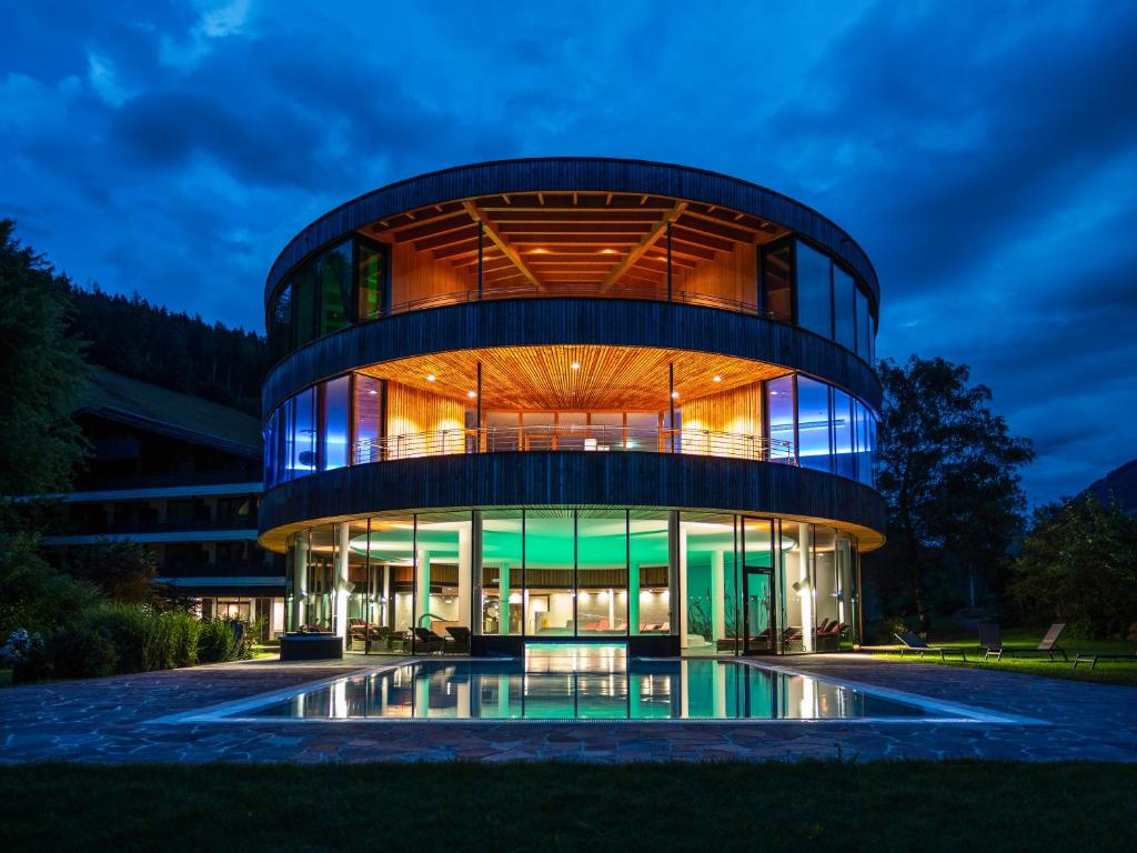 a building with a glass facade at night at Gesundhotel Bad Reuthe in Vorderreuthe