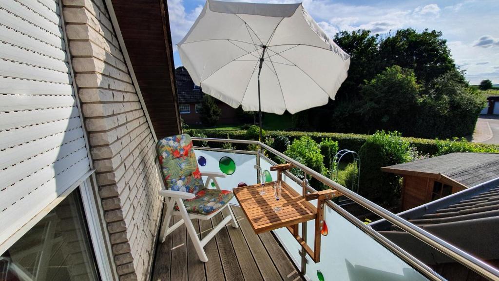 a chair and an umbrella on a balcony at Klimatisierte Wohnung Kastanie mit Balkon in Löhne