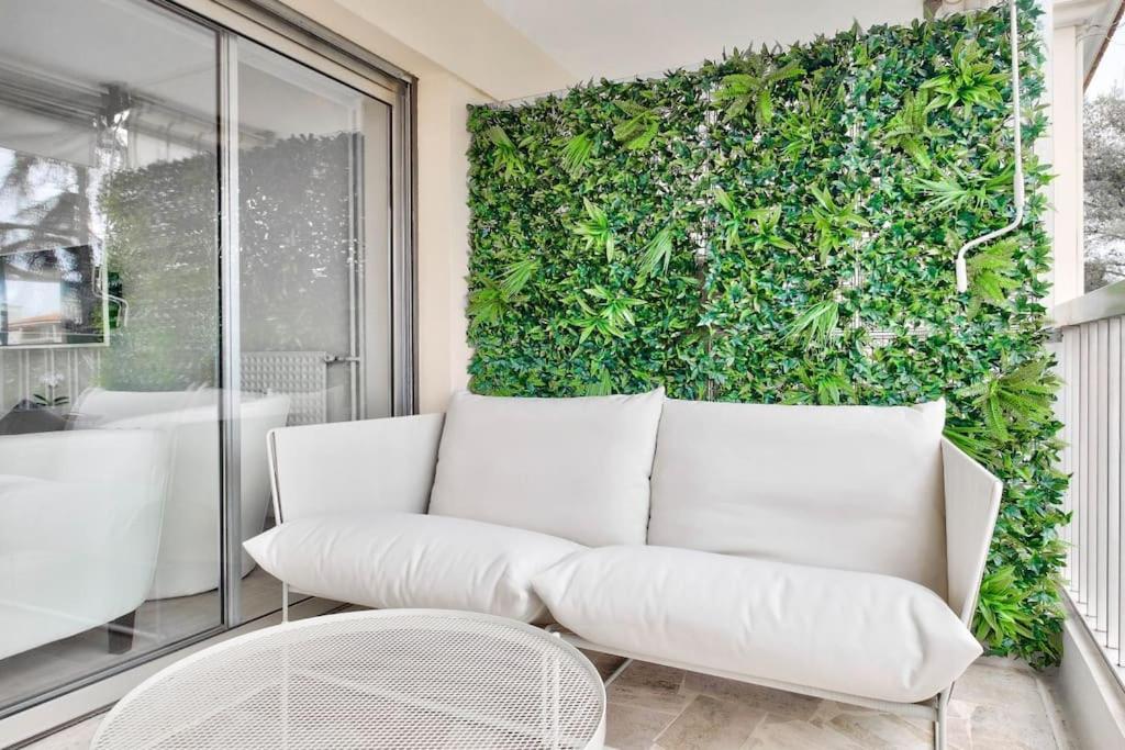 - un canapé blanc devant un mur vert dans l'établissement Superbe studio avec terrasse à 10 min de la plage, à Cannes