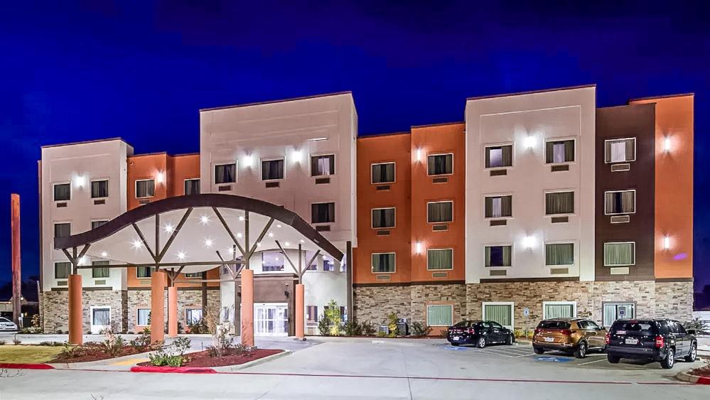 a large building with cars parked in a parking lot at Del-Mar Airport Inn & Suites in Shreveport