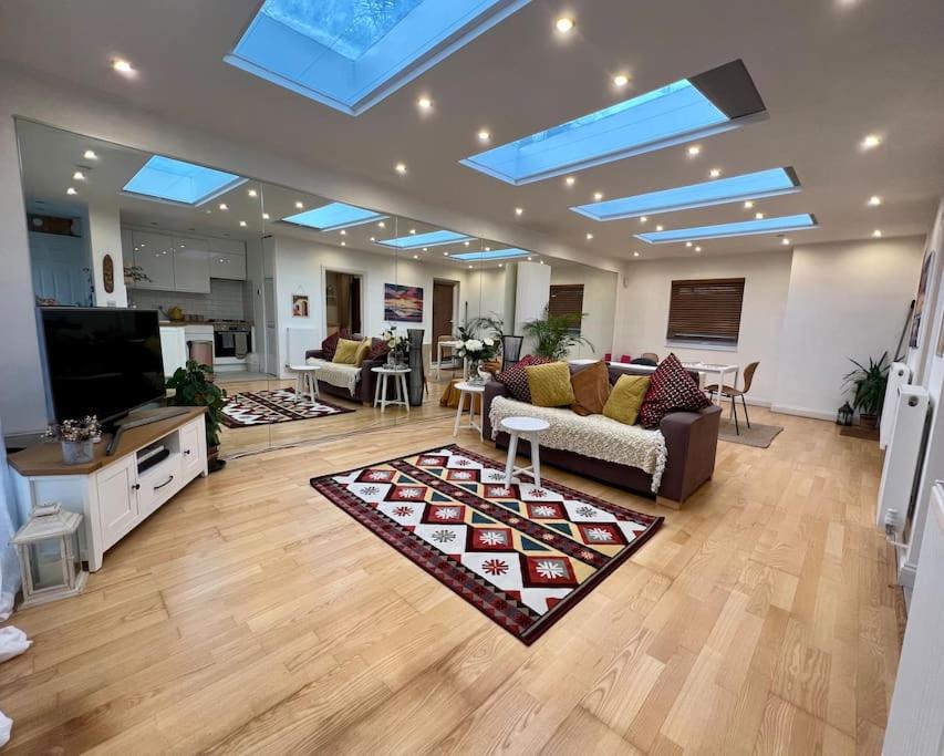 a large living room with a couch and a tv at Sunny London Garden Apartment in London