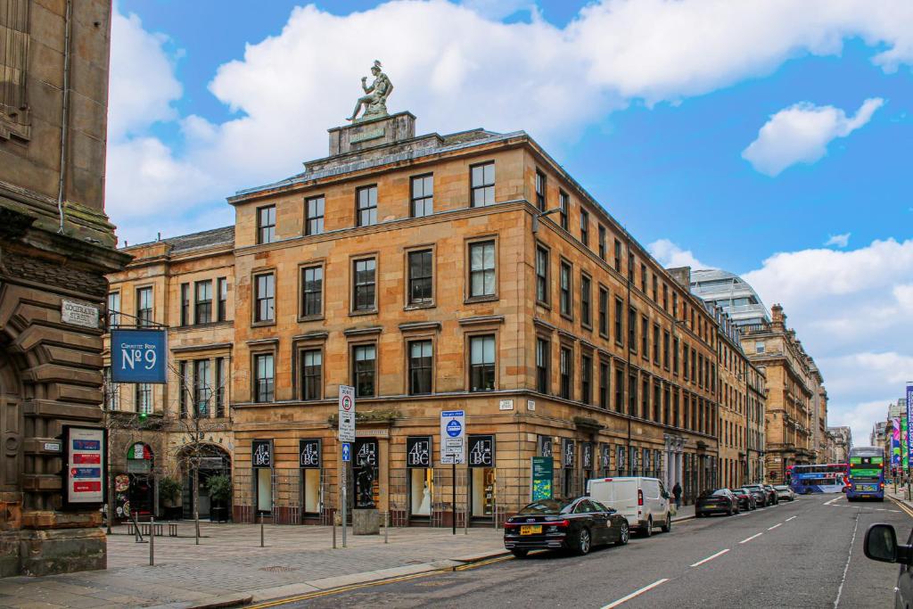 a large brick building with a statue on top of it at Stylish Merchant City Apartment in Glasgow