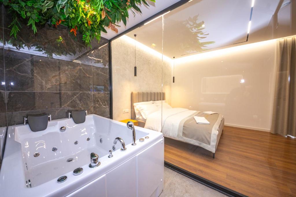 - une salle de bains avec baignoire et un lit dans une chambre dans l'établissement Hotel Riviera, à Tirana