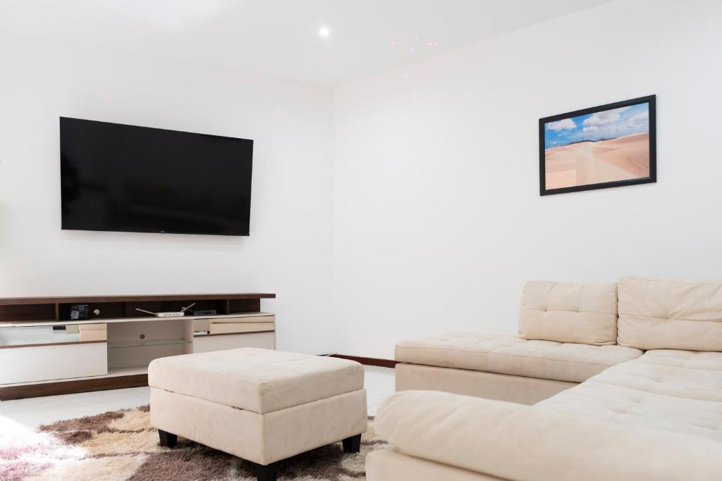Il comprend un salon doté d'un canapé et d'une télévision à écran plat. dans l'établissement 5 bdr house near Praça Center, AC & Wifi - LCGR, à Praia