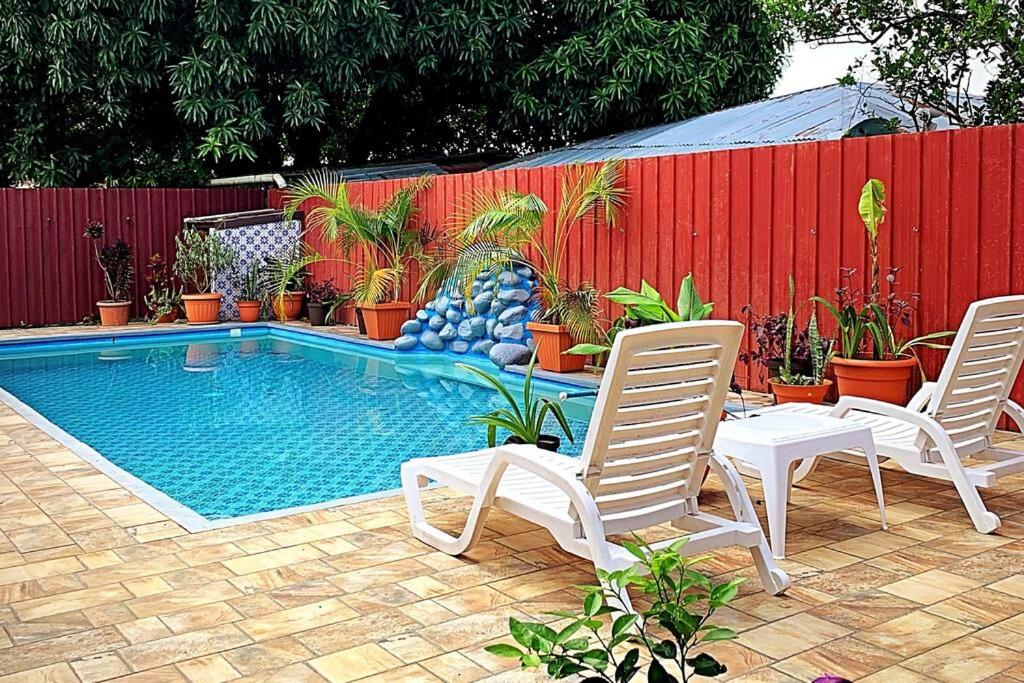 a swimming pool with chairs and a fence with plants at Casa Piscina - House with a pool in David in David