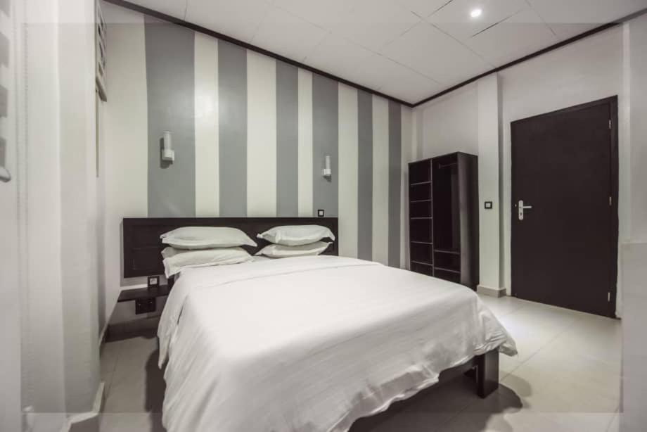 a bedroom with a white bed and striped walls at VDR Hotel in Douala
