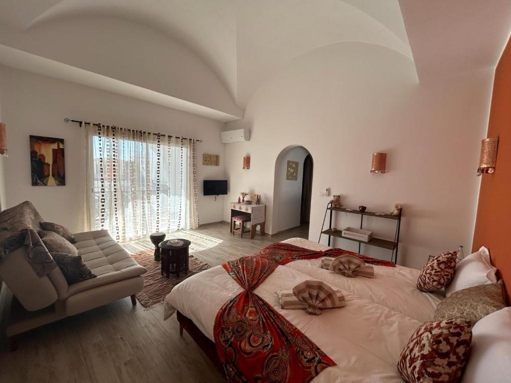 a bedroom with a large bed and a living room at Dar El Kahina Djerba in Mezraya