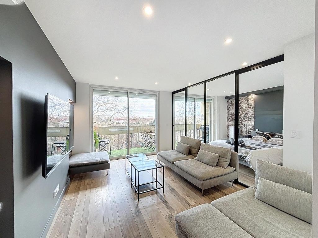 un salon avec un canapé et un lit dans l'établissement Le Balcon - Vue sur canal de Brienne, à Toulouse