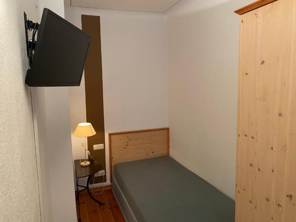 a small bedroom with a bed and a tv on the wall at Hotel Weinstube am Markt in Gerolzhofen