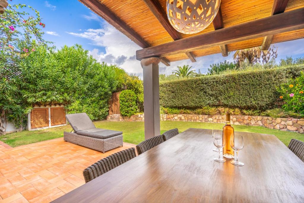 un tavolo in legno con bicchieri da vino su un patio di Splendida Villa a Notteri, Spiaggia di Porto Giunco a Notteri