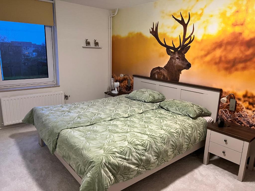 een slaapkamer met een bed met een hertenkop aan de muur bij B&B Tina in Sneek