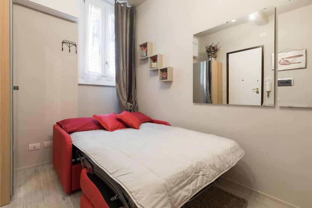 Schlafzimmer mit einem Bett mit roten Kissen und einem Spiegel in der Unterkunft Reparata- Cozy nest looks for solo traveller in Florenz