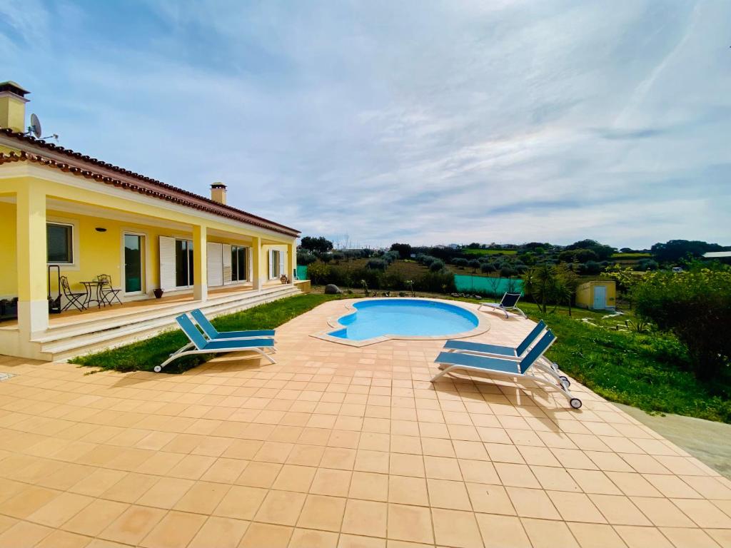 a patio with two chairs and a swimming pool at Pôr-do-sol Villa in São Pedro do Corval