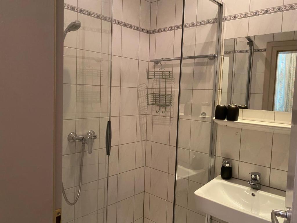 a shower with a glass door next to a sink at Hotel Weinstube am Markt in Gerolzhofen