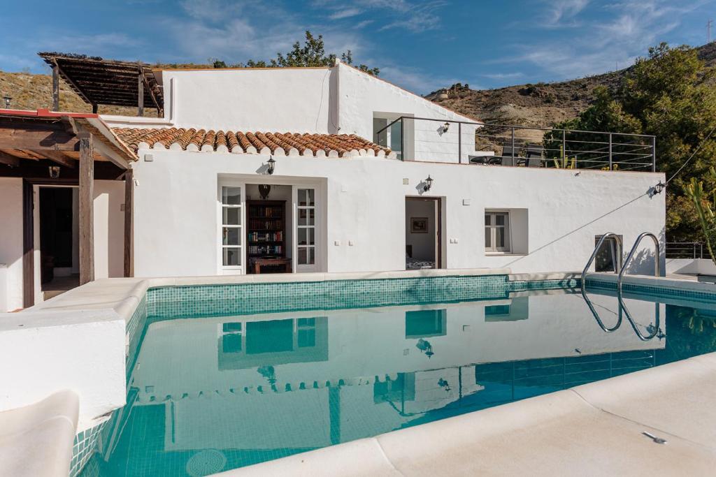 a villa with a swimming pool in front of a house at Finca La Herradura in La Herradura