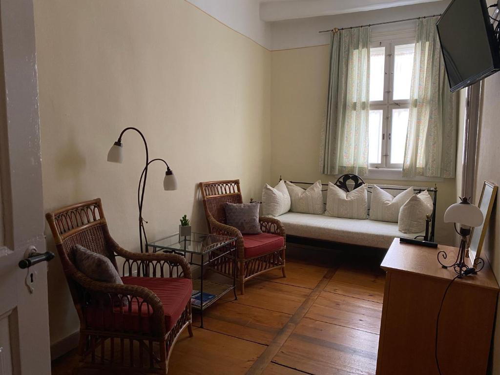 a living room with a white couch and chairs at Hotel Weinstube am Markt in Gerolzhofen