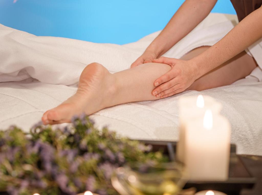 a woman sitting on a bed with her leg in at Hotel Dom Goncalo & Spa in Fátima