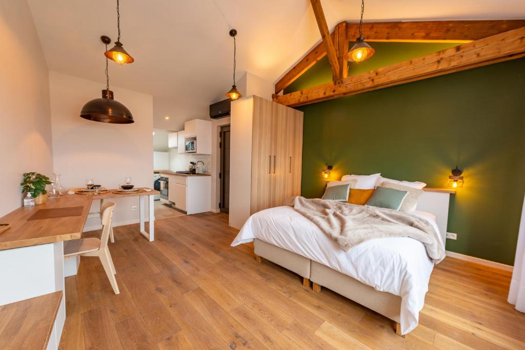 ein Schlafzimmer mit einer grünen Wand, einem Bett und einem Schreibtisch in der Unterkunft Studio Le Vau in Bagneux