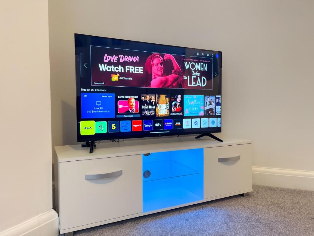 Elle comprend une télévision à écran plat installée au-dessus d'un centre de divertissement blanc. dans l'établissement Wembley Stadium, Modern&Cozy Apartment with Garden, à Londres