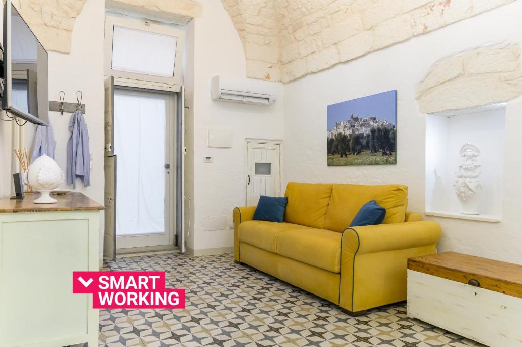 uma sala de estar com um sofá amarelo e uma mesa em La Dimora del Tempo by Wonderful Italy em Ostuni