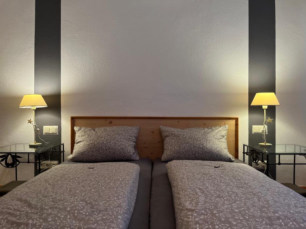 two beds in a bedroom with two lamps on tables at Hotel Weinstube am Markt in Gerolzhofen