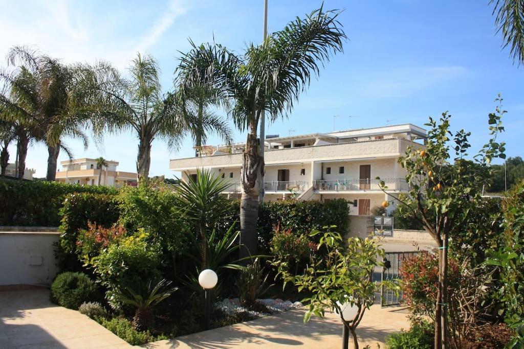 a building with palm trees and plants in front of it at Villetta con patio e giardino in Gallipoli